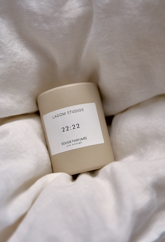 Lagom Studios_Vegane Duftkerze 22:22 in beigem Keramikgefäß in Leinenbettwäsche im Bett im Schlafzimmer